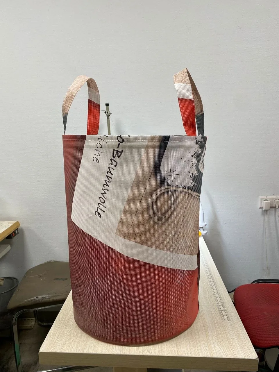 Tall freestanding basket sewn from red and beige advertising banner mesh